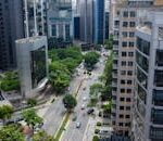 Aerial view of a bustling city street lined with modern skyscrapers and green trees.