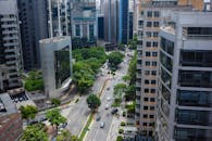 Aerial view of a bustling city street lined with modern skyscrapers and green trees.